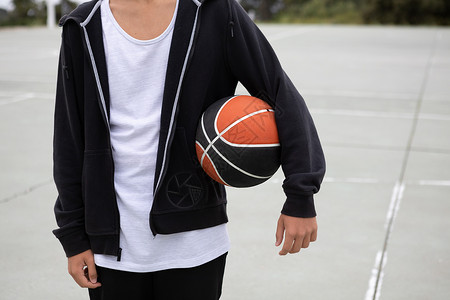 在篮球场的男少年运动员手臂下有球中区图片