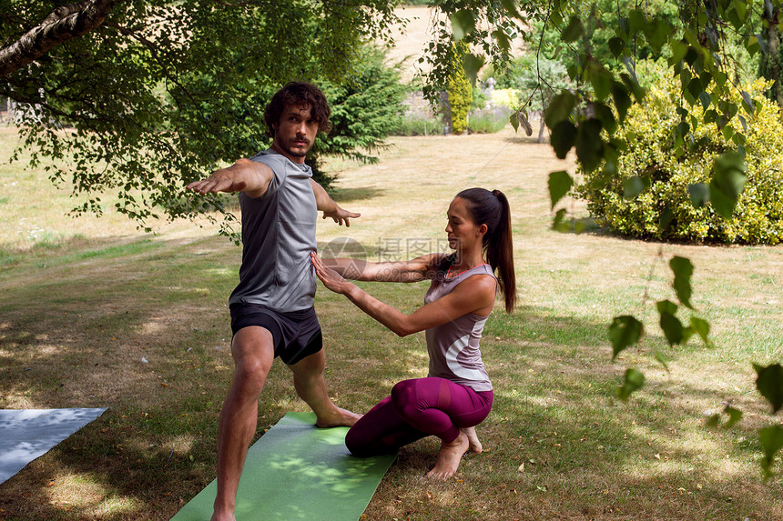 女瑜伽老师在花园教年轻男子瑜伽图片