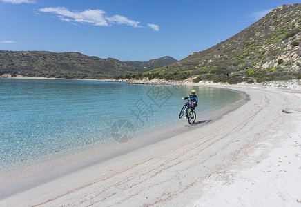 嘉撒丁岛意大利撒丁岛比亚西米乌斯海滩上骑车的人背景