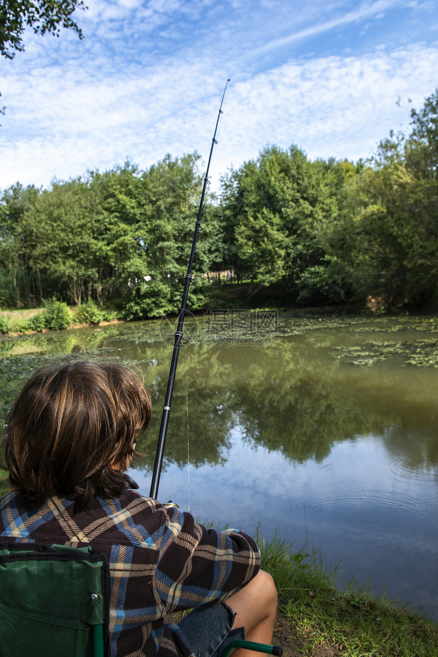 在联合王国伯恩茅斯湖边钓鱼的男孩图片