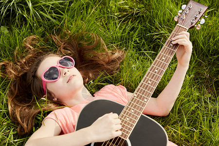 女孩在草地上弹吉他图片