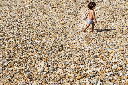 小男孩在小石头沙滩上行走图片