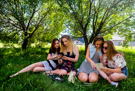 女人在城市公园草地上玩手机图片