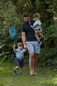 父亲和儿子拿着网兜在公园捕鱼背景图片