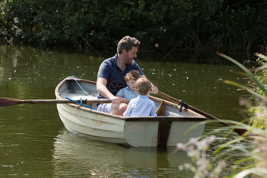 父亲和孩子在湖中划船图片