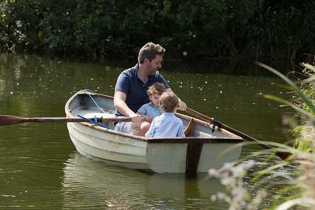 父亲和孩子在湖中划船图片
