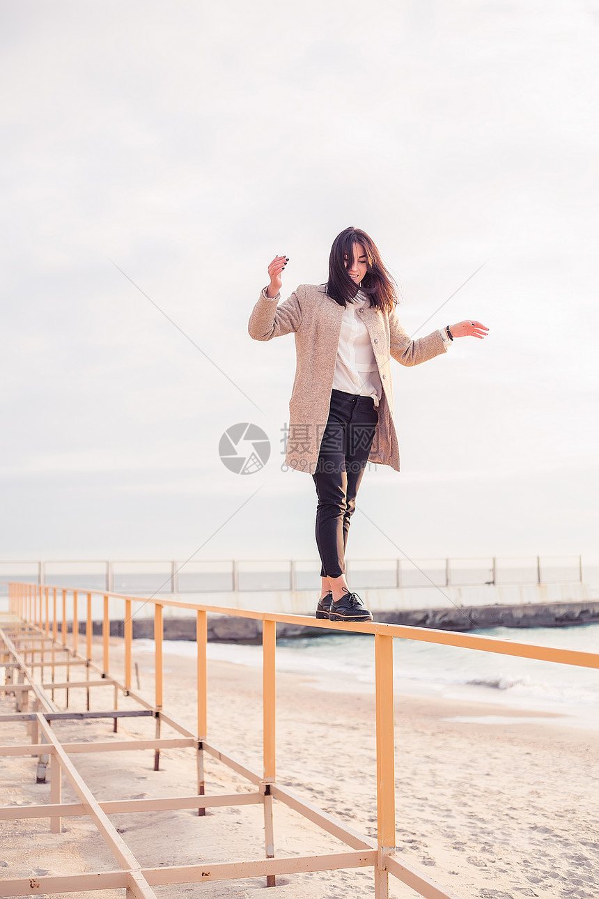 妇女在海滩的扶手上保持平衡图片