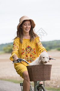田园女性骑着自行车载着宠物狗图片