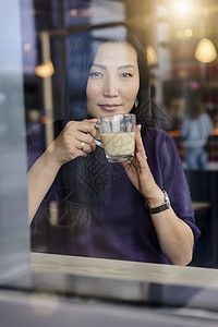 成年女人从咖啡厅窗口向外看图片