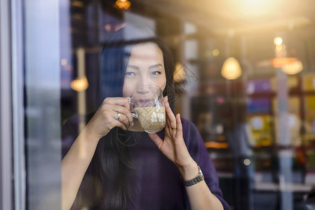 成年女子在咖啡馆的橱窗座位喝咖啡图片