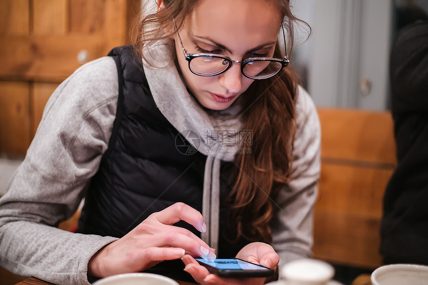 在咖啡馆使用手机的年轻妇女图片