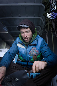 年轻男攀岩者在野营车厢中准备攀岩设备图片