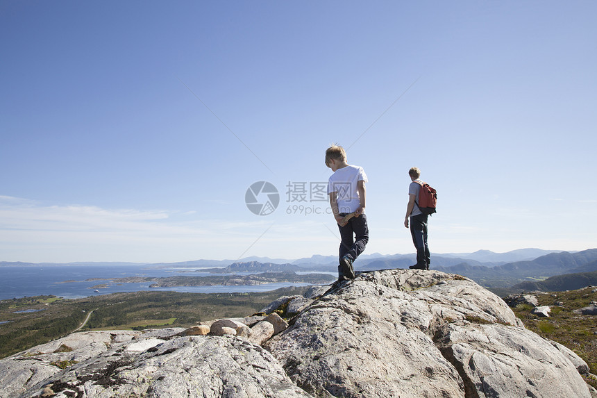 男孩和父亲站在岩石上向外望去图片