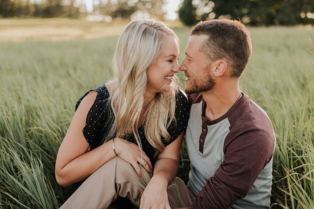 浪漫的男人和女友在长草地上面对面微笑图片