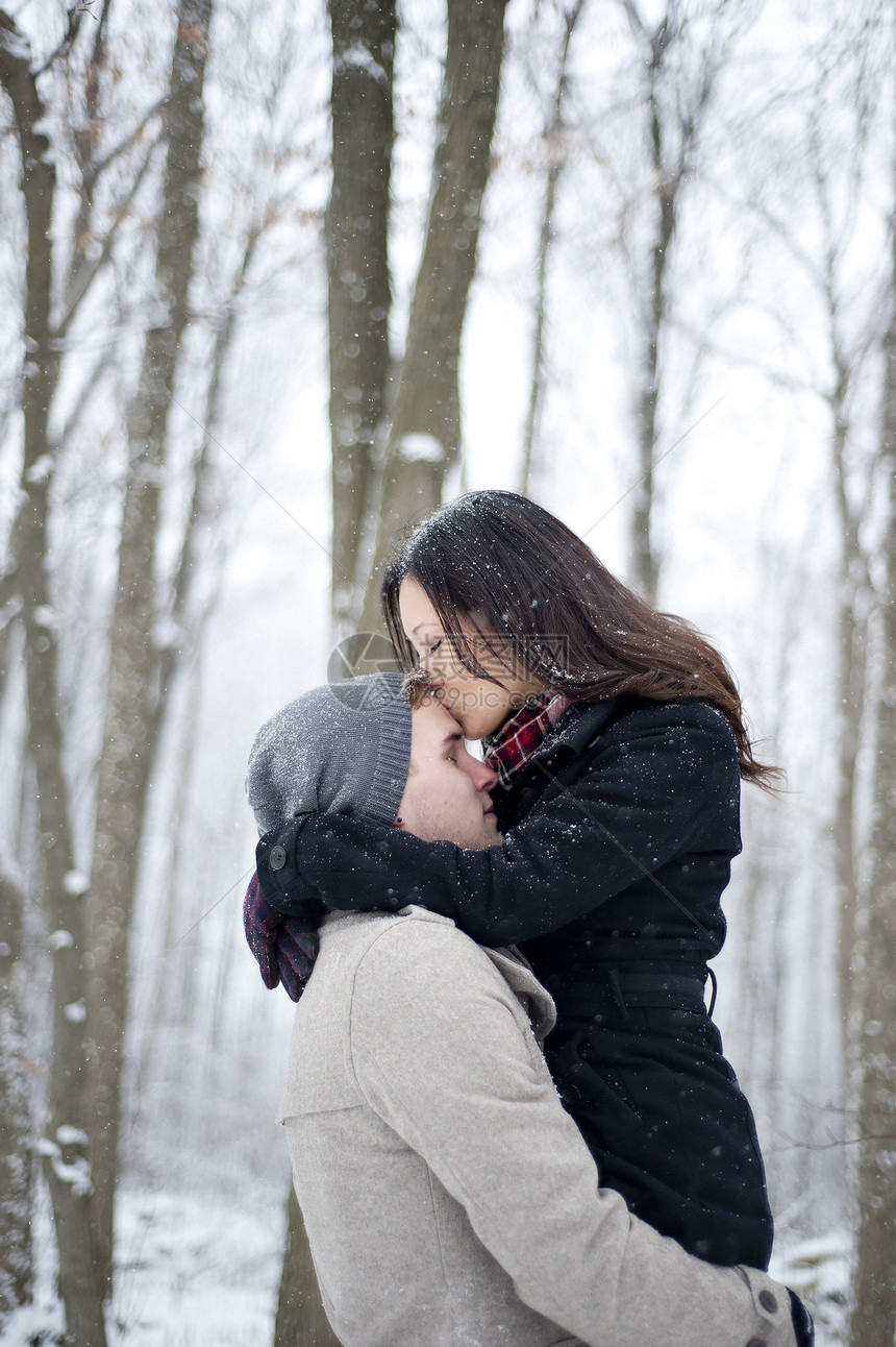 在加拿大安略省雪覆盖森林中亲男友前额的浪漫女青年加拿大安略省图片