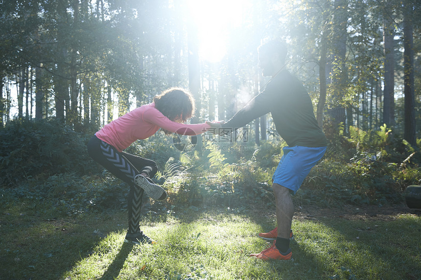 男和女选手伸展双腿在日光林中升温图片