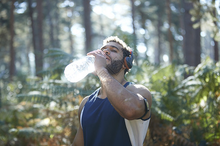 日光林中男跑者饮用瓶装水图片