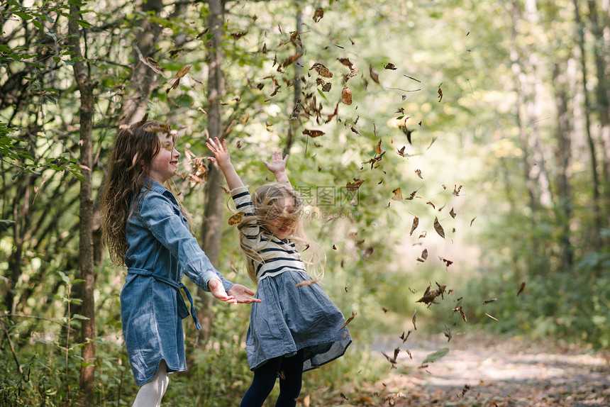姐妹们在森林中把叶子扔在空气中图片