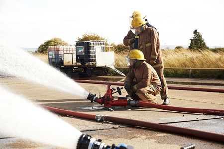 消防员在喷水的消防水带旁图片