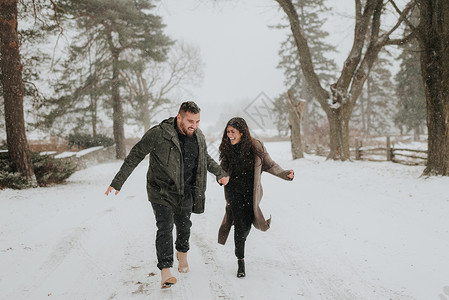 在加拿大乔治敦的雪地上手牵手奔跑的一对夫妇图片
