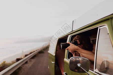 美国加利福尼亚州文图拉沿海公路上乘坐面包车旅行的人用相机拍照图片