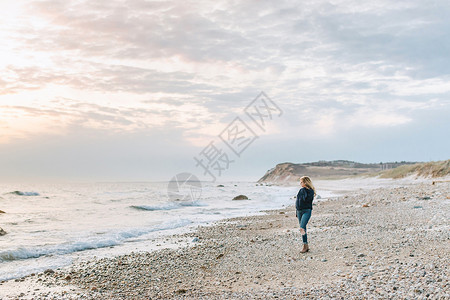 日落梅内姆沙美国马萨诸塞州玛莎葡萄园梅内姆沙一名年轻女子在海滩眺望大海背景