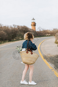 灯塔在前方一名年轻女子在乡村道路上看着灯塔背景