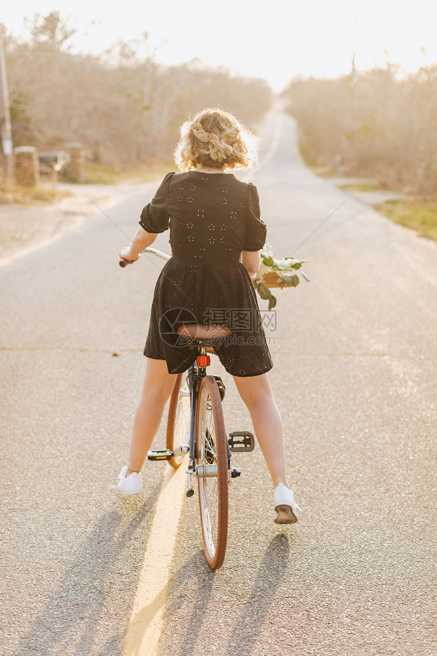 农村公路上骑自行车的年轻女子图片
