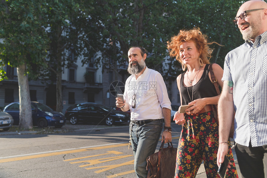 成年妇女和朋友在城市人行道上漫步聊天图片