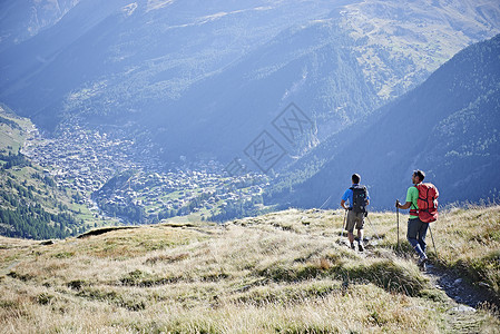 在草悬崖上看山谷的登山者瑞士瓦莱州图片