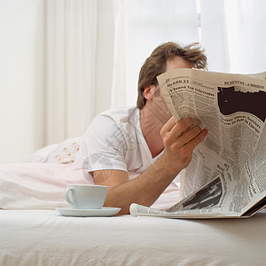 男人在床上喝茶看报纸图片