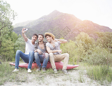 三个年轻人坐在独木舟上拍着自己肖像照片高清图片
