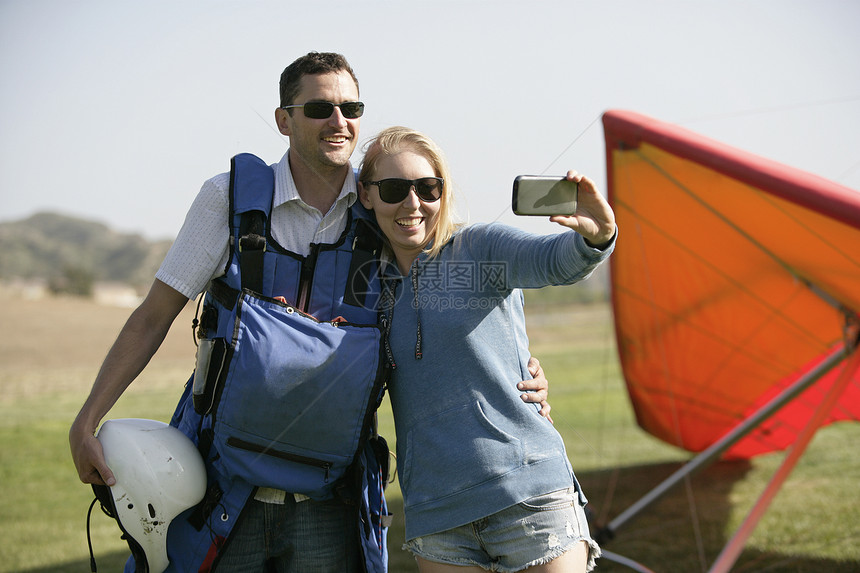 情侣在滑翔机前面自拍图片