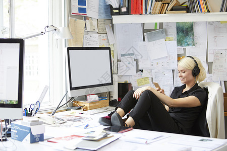 女设计师在办公桌上翘着脚看手机图片