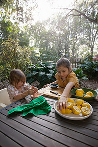 两个年轻姐妹在花园桌前准备柠檬汁图片