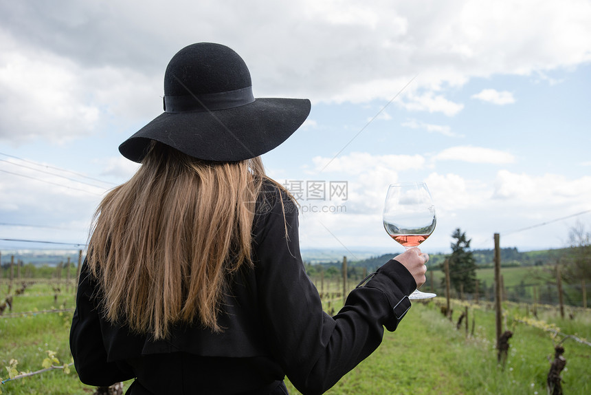 女人站在葡萄园里拿着酒杯背影图片