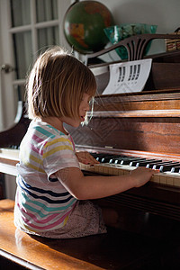 在家里弹旧钢琴的女孩背景图片