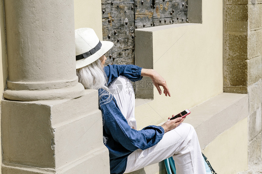 意大利托斯卡纳教堂外拿着手机听歌的女人图片