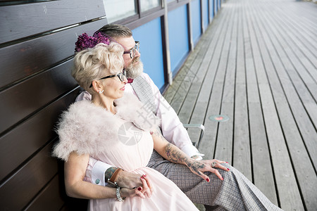 打扮复古的老年夫妻坐在码头长椅上图片