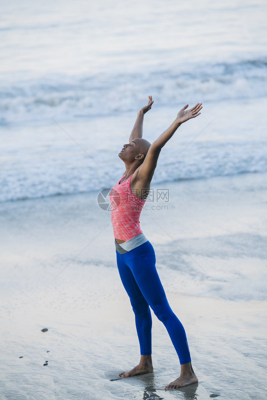 年轻女子在海滩上运动伸展图片