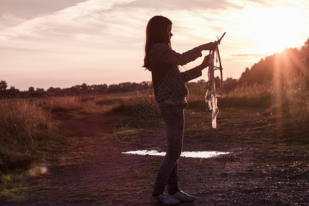 日落时少女在泥土路上准备放飞风筝图片