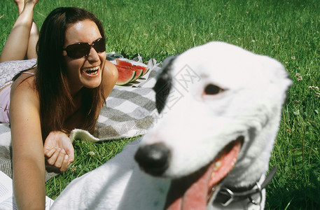 和狗一起在草地上玩的女人在笑图片