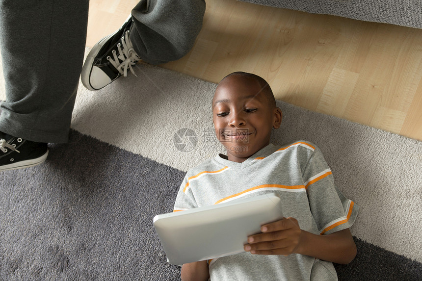 男孩用数字平板电脑躺在地上图片