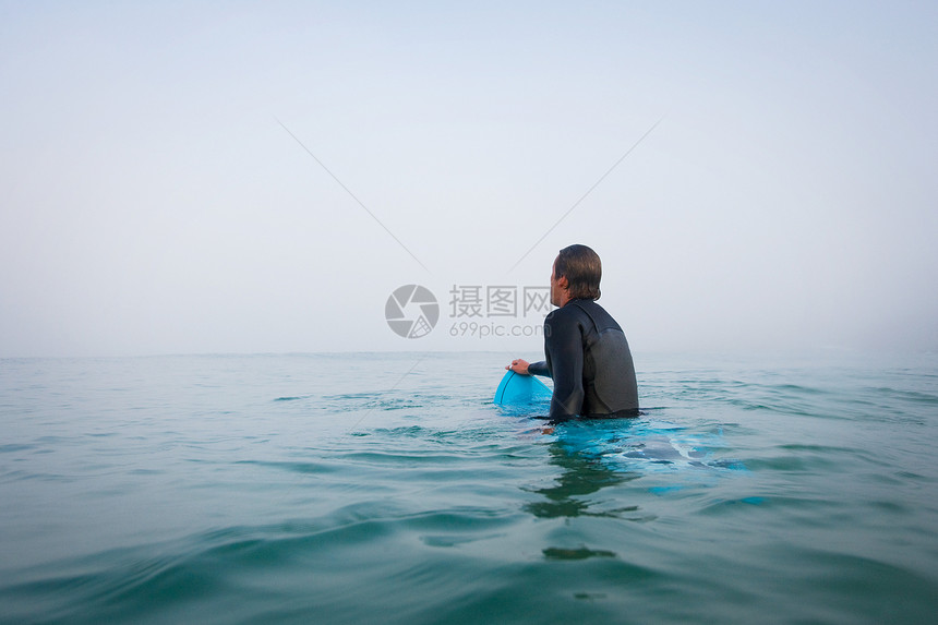 坐在水中冲浪板上的男人图片