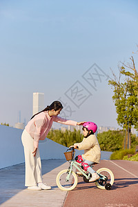 骑车郊游的女孩妈妈陪伴女儿骑自行车背景