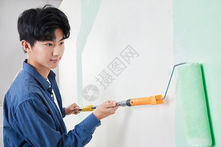青年男性使用涂料滚筒刷墙背景图片