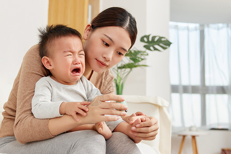 帮妈妈做事母亲帮哭泣的孩子修剪指甲背景