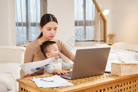 居家办公裹着毛毯的女性母亲抱着孩子居家办公背景