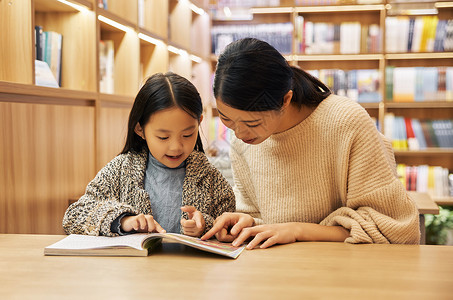 亲子图书馆妈妈女儿坐在书店里阅读背景
