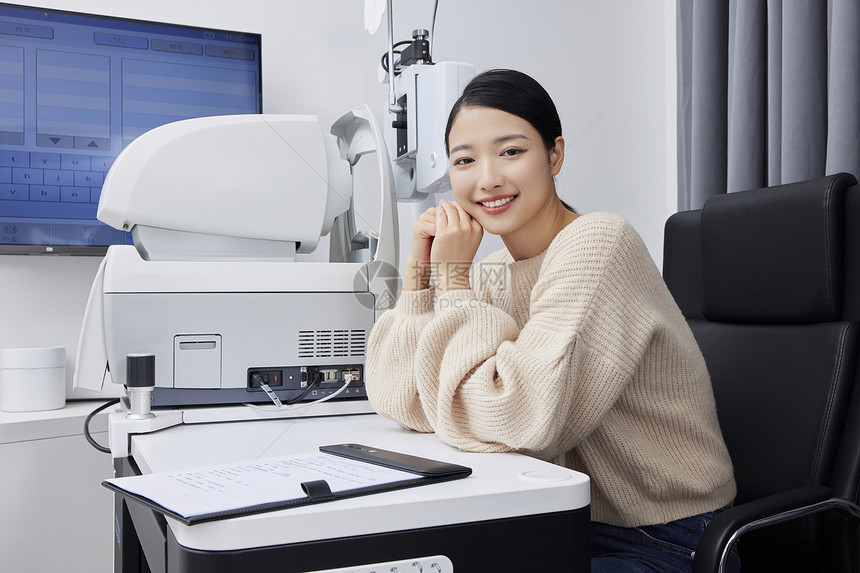 检查视力的女性坐在验光机器前面带微笑图片